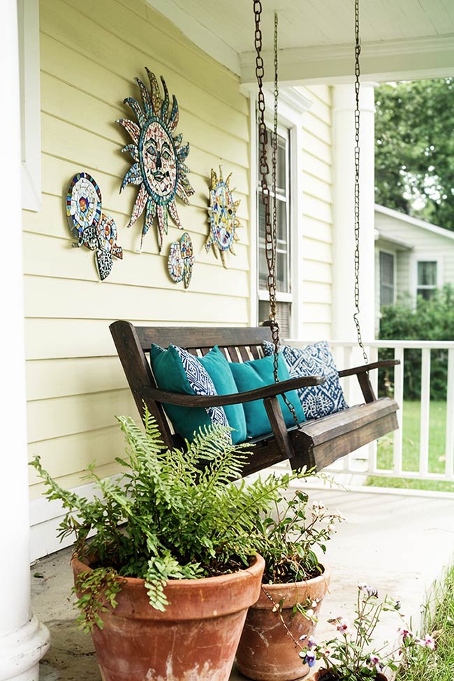 Whimsical Sun Art and Cozy Swings on a Welcoming Front Porch